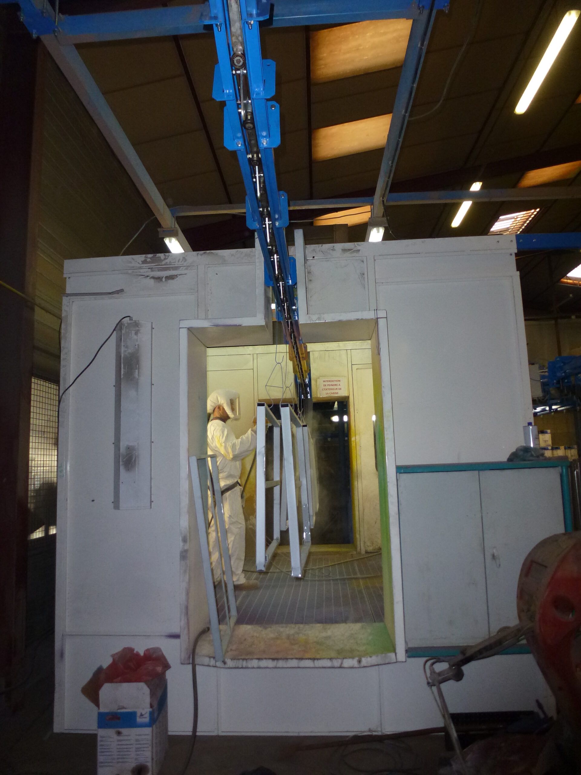 Convoyeur monorail dans une cabine de peinture